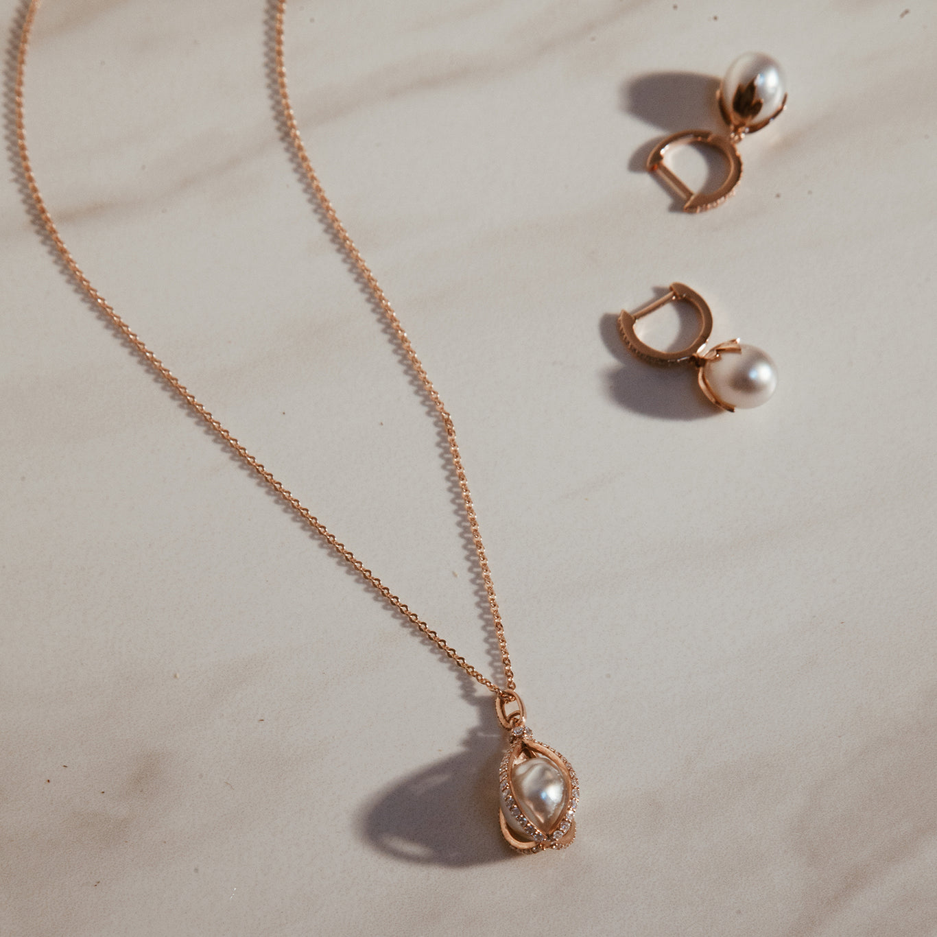 The Pearl Leaf Huggies shown in rose gold with the Pearl Cage Necklace.