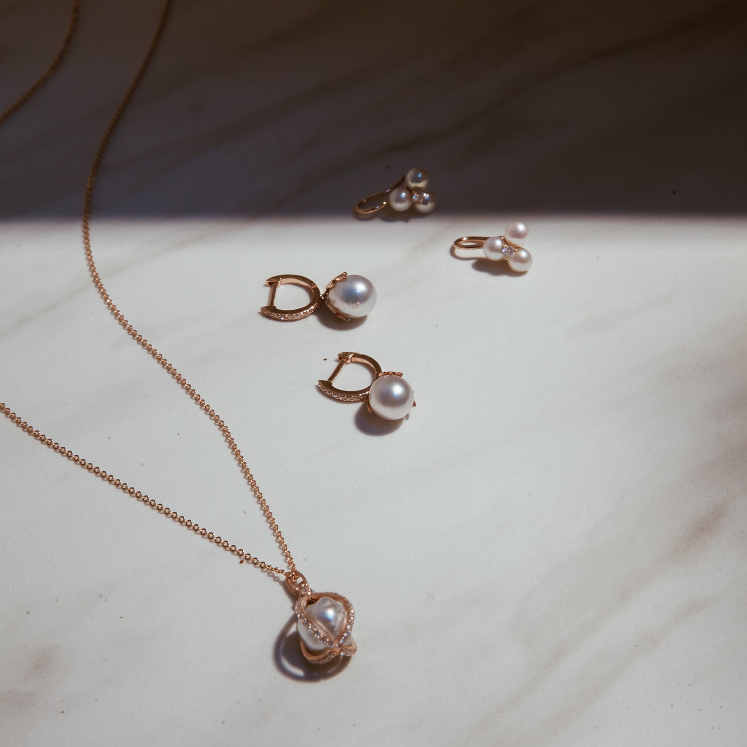 Our Tri Pearl Earrings shown with the Pearl Leaf Huggies and Pearl Cage Necklace.
